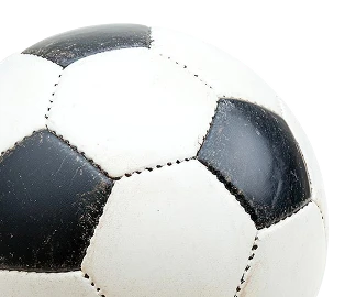 Un ballon de football classique noir et blanc à la texture usée flotte sur un fond noir uni, évoquant un sentiment de jeu et d'énergie intemporels. 