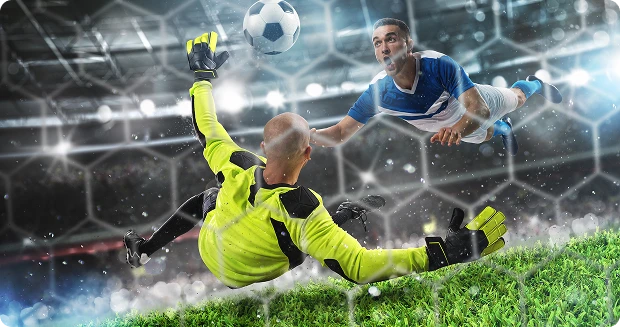 Le gardien de but, vêtu de jaune vif, saute pour bloquer le ballon, tandis qu'un joueur adverse en bleu plonge, visant le but. Action intense sous les projecteurs du stade.